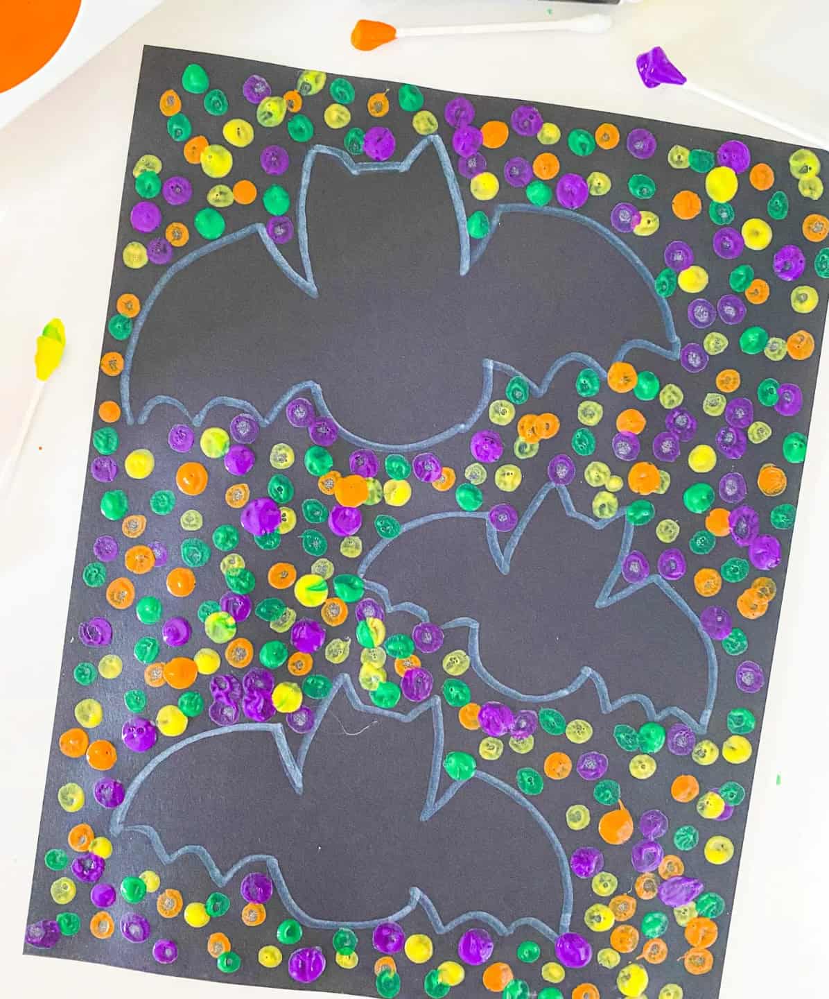 Colorful Q-tip bat painting on dark paper