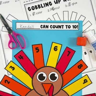 Turkey number order craft on blue paper with printable Gobbling Up Numbers worksheets, scissors, and glue.