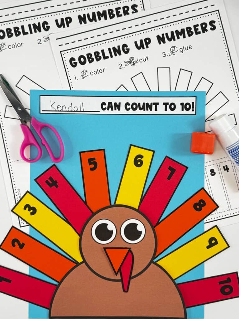 Turkey number order craft on blue paper with printable Gobbling Up Numbers worksheets, scissors, and glue.