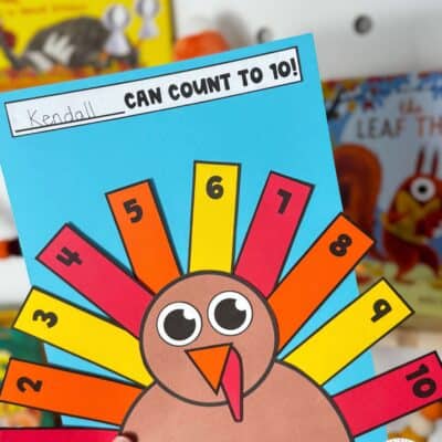 Paper turkey counting craft with colorful feathers numbered 1–10 on blue paper beneath a Can Count to 10 label.